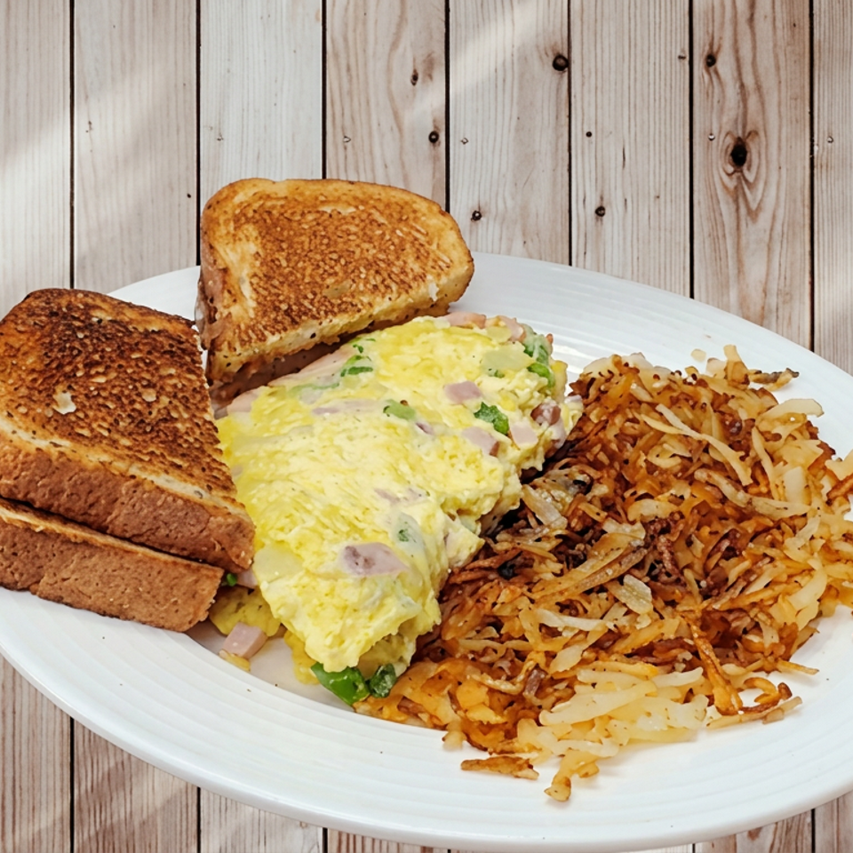 Plate of scrambled eggs with onions, toasted bread, and crispy hash browns on a wooden table.